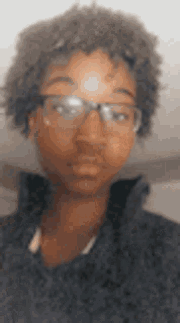 a blurry picture of a young man wearing glasses and a sweater .
