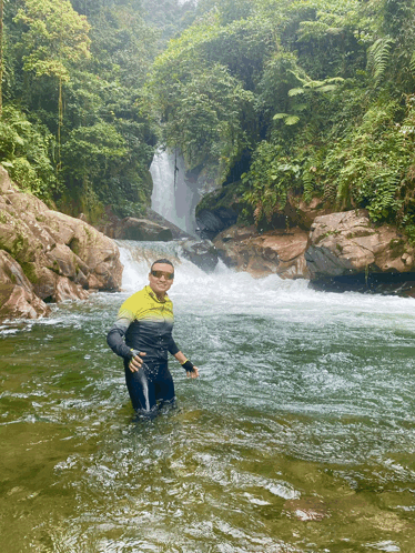 a man in a yellow and black shirt is standing in a river