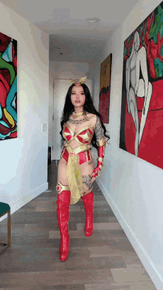 a woman in a wonder woman costume is standing in a hallway holding a sword .