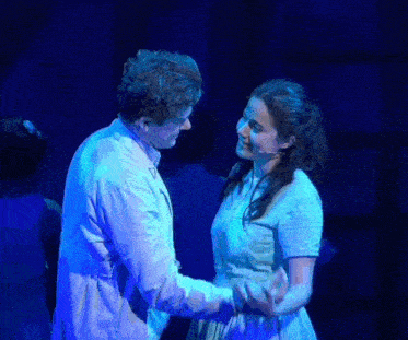 a man and a woman are looking into each other 's eyes on stage