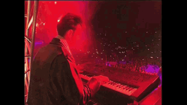 a man is playing a keyboard in front of a crowd of people .