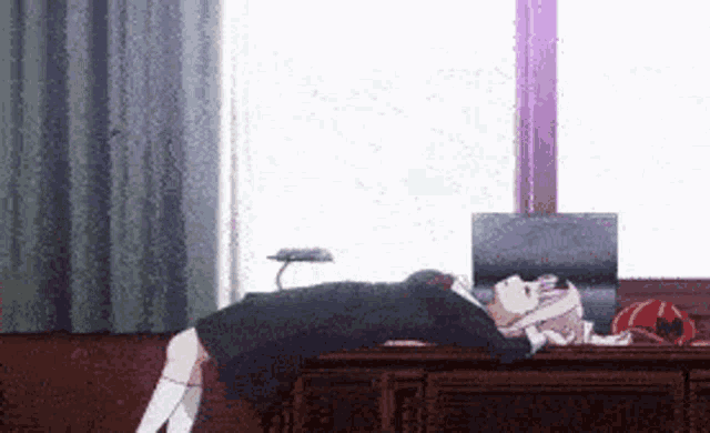 a girl is laying on a desk in front of a window in a room .
