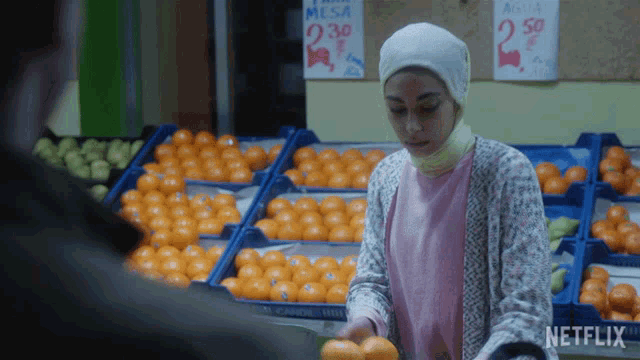 a woman holding oranges in front of a sign for mesa
