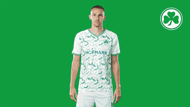 a man wearing a green and white hofmann jersey stands in front of a green background