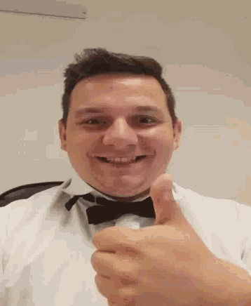 a man wearing a bow tie gives a thumbs up