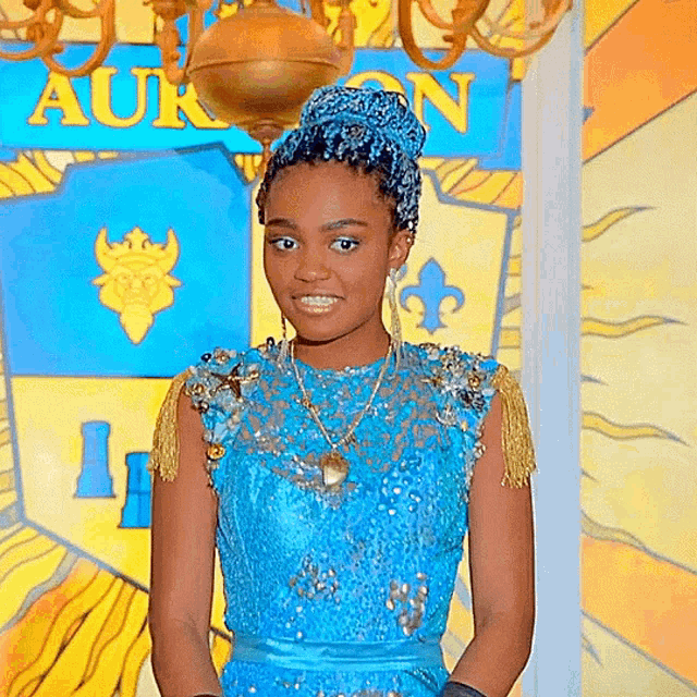a girl in a blue dress stands in front of a wall with the word auron on it