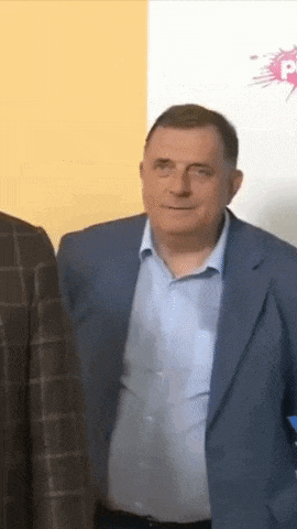 a man in a blue suit and white shirt is standing next to another man in a plaid jacket .