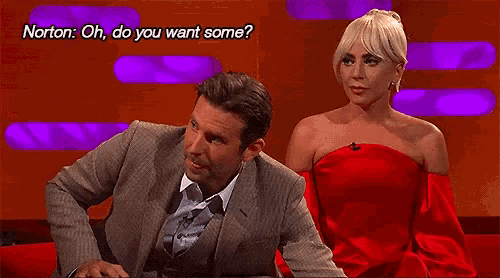 a man in a suit is sitting next to a woman in a red dress who is asking him if he wants some .