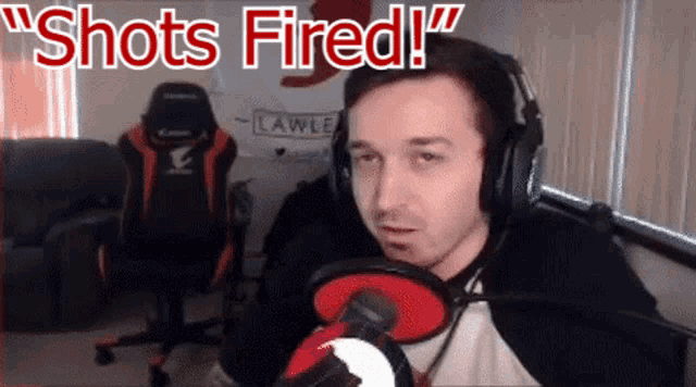 a man wearing headphones stands in front of a microphone with the words " shots fired " written above him