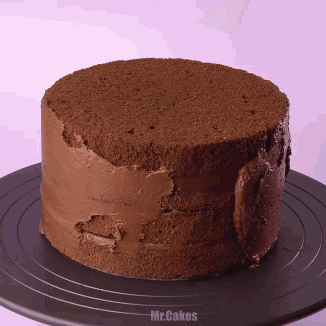 a chocolate cake sitting on a black plate with mr.cakes written below it