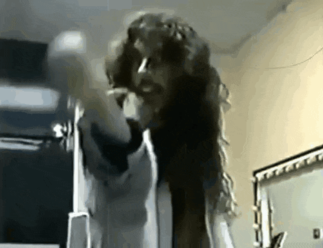 a man with long hair and a beard is standing in front of a mirror in a room .