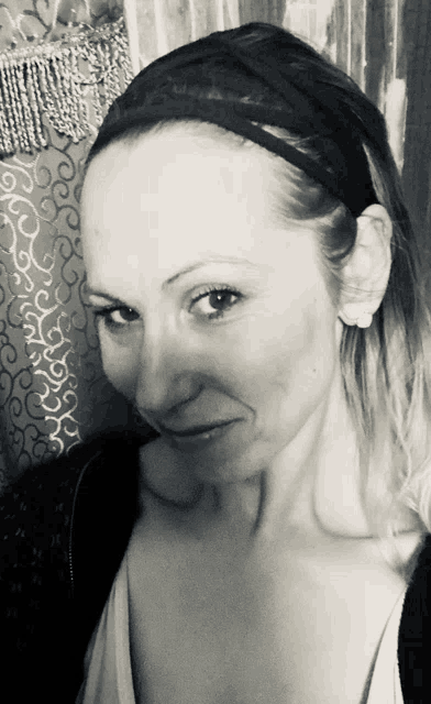 a woman wearing a headband and earrings looks at the camera in a black and white photo