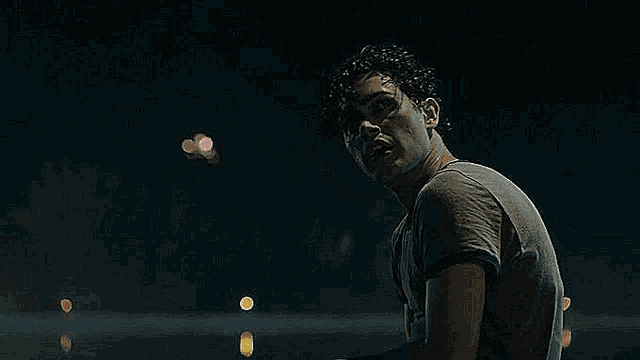 a man is sitting in front of a fireworks display at night .