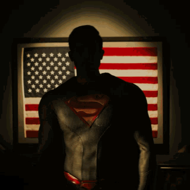 a man in a superman suit is standing in front of an american flag