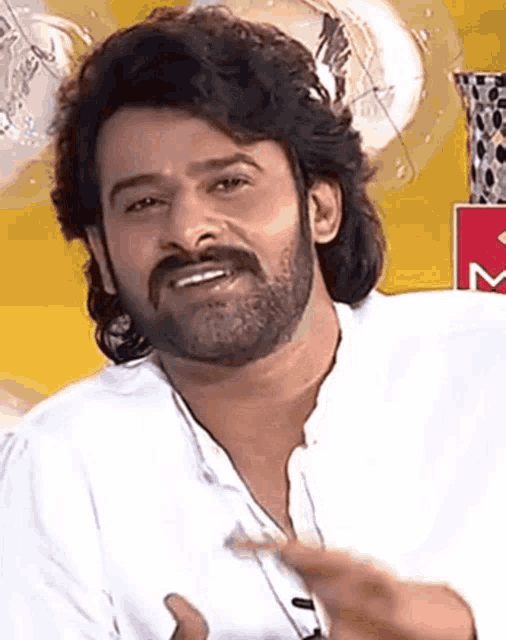 a man with a beard wearing a white shirt is smiling .
