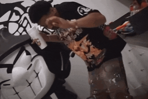 a man in a black shirt with a skull on it drinks from a cup
