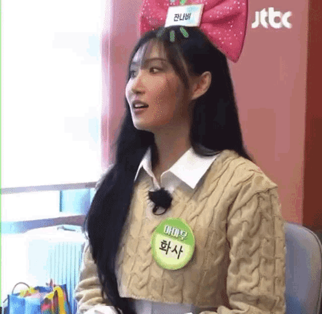 a woman wearing a sweater and a name tag with a bow on her head .