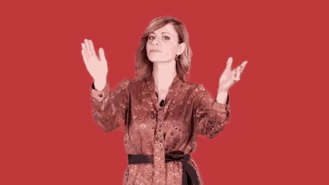 a woman in a floral dress holds her hands up in the air