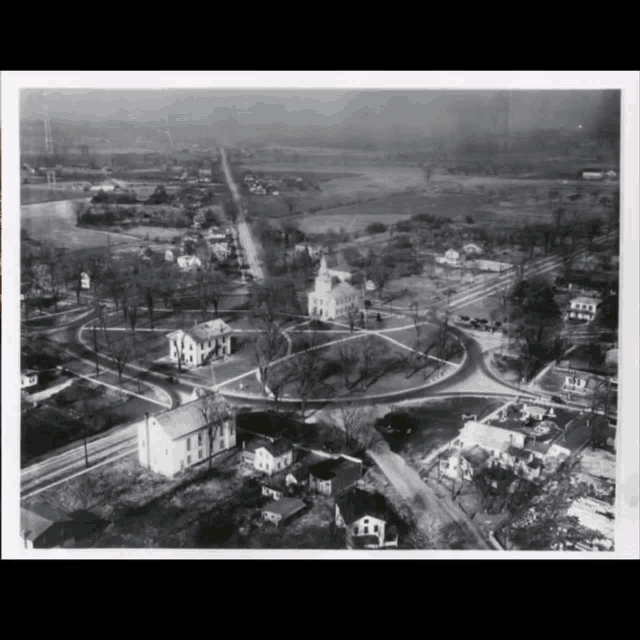 an aerial view of a small town with a church in the middle