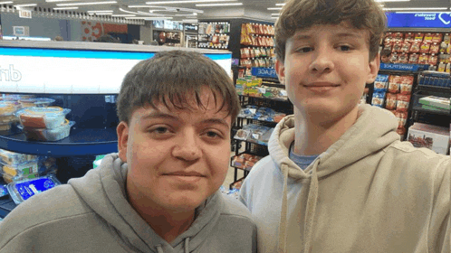 two boys are posing for a picture in a grocery store with a sign that says ' frozen dinners ' on it