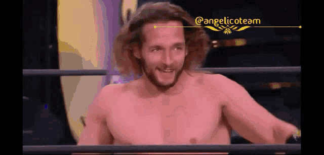 a man without a shirt is standing in a wrestling ring smiling .