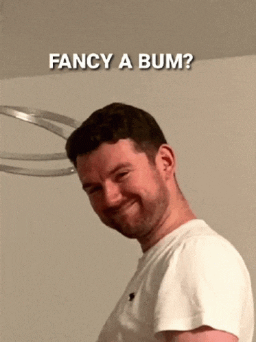 a man in a white shirt is making a funny face with the words fancy a bum behind him
