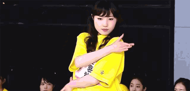 a girl wearing a yellow shirt with a pink tag that says akb48
