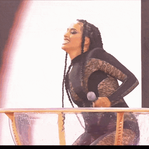 a woman with braids is holding a microphone while standing in a glass bowl