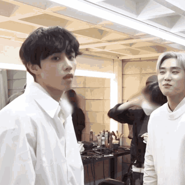 two young men standing next to each other in a room