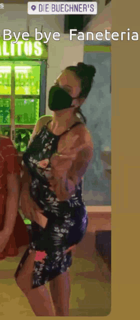a woman wearing a face mask is holding a child in front of a sign that says die buechner 's
