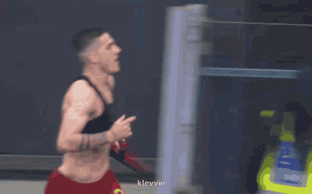 a man with a tattoo on his chest is running in a blurry photo with the name klievin visible in the corner