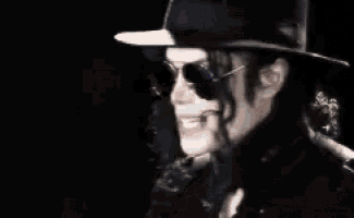 a man wearing a black hat and sunglasses smiles