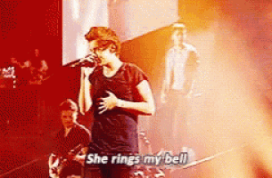 a man singing into a microphone on a stage with the words she rings my bell .