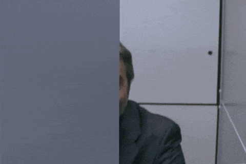 a man in a suit is peeking out of a bathroom stall