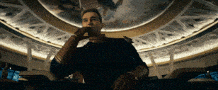 a man is sitting in a room with a ceiling that has a painting of a woman on it