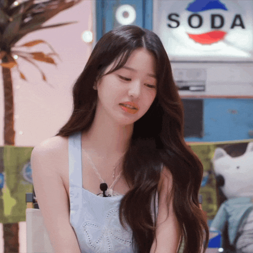 a woman stands in front of a sign that says soda