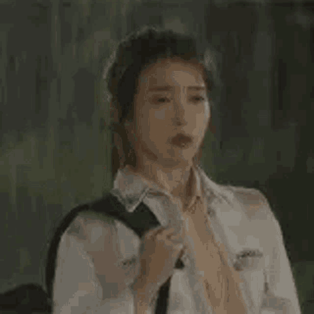 a woman wearing a white shirt and tie is holding a black backpack .