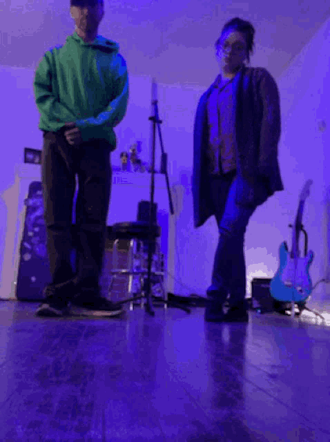 a man in a green hoodie is standing next to a woman in a blue jacket