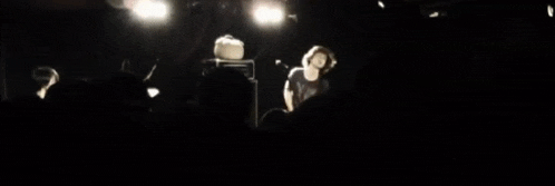 a group of people are standing in a dark room watching a performance
