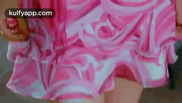 a woman is wearing a pink dress with ruffles and a swirl pattern .