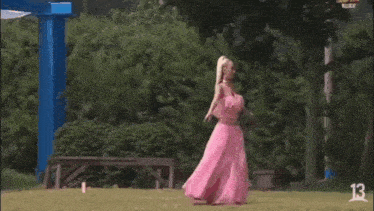 a woman in a pink dress is dancing on a field .