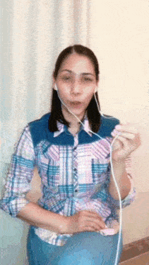 a woman wearing headphones and a plaid shirt is holding a wire .