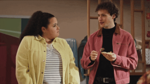a man in a pink jacket and a woman in a yellow jacket are looking at each other