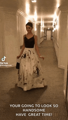 a woman in a long dress is walking down a hallway