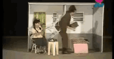 a man is standing next to a woman sitting in a chair in a room .