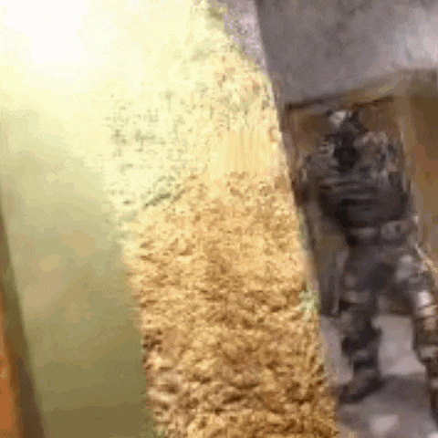 a soldier is standing in front of a pile of wood .
