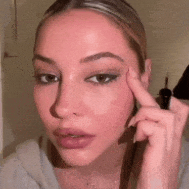 a woman is applying eyeliner to her eyebrows .
