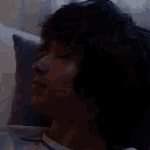 a close up of a person 's face with a pillow in the background