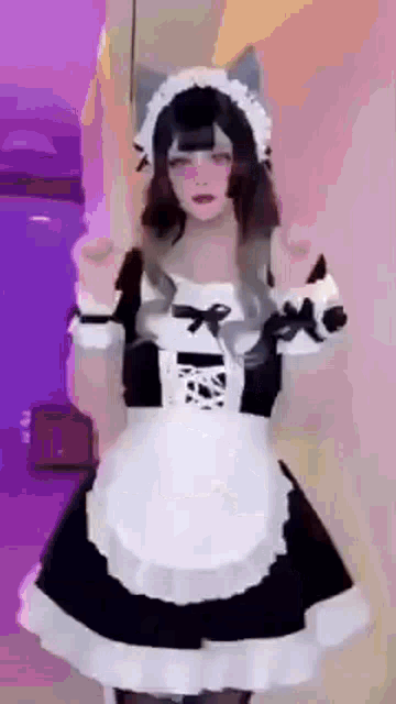 a woman in a maid costume is standing in front of a wall .