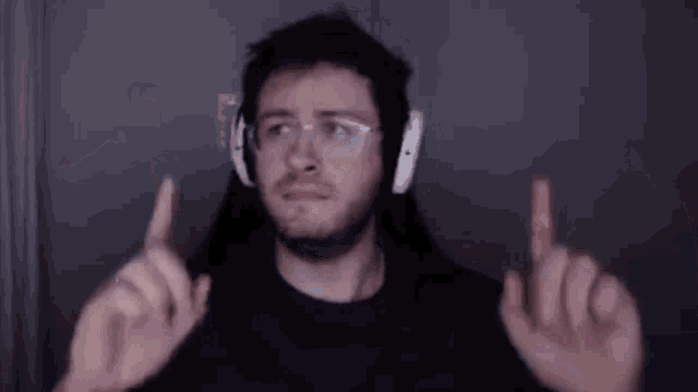 a man wearing headphones and glasses is making a funny face while giving the middle finger .